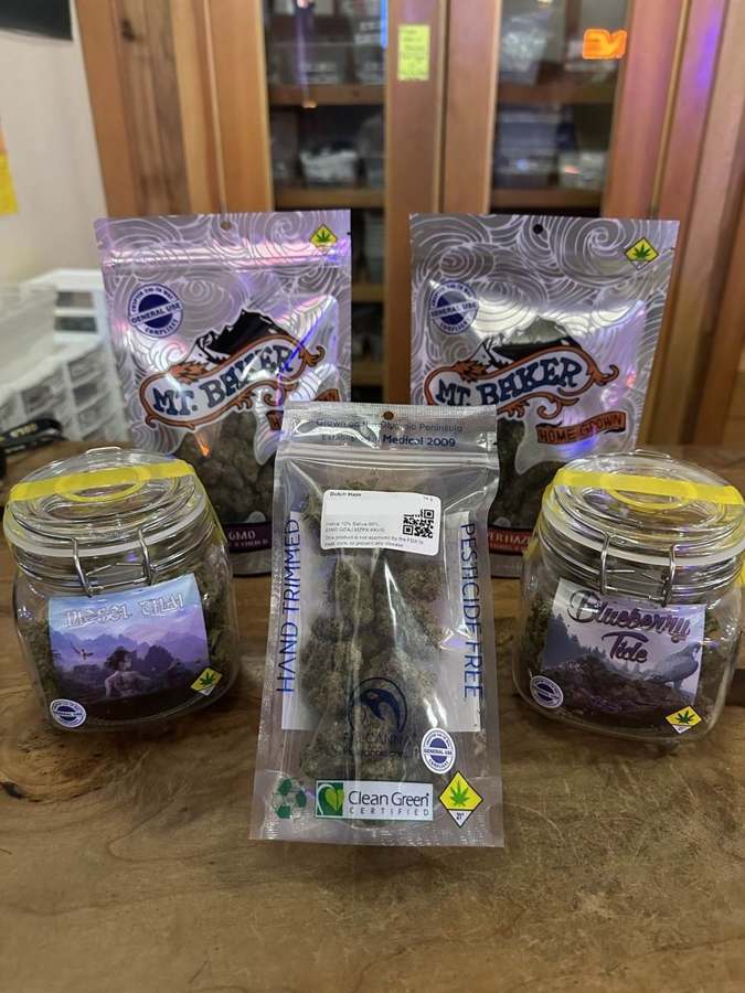 Bagged and jarred Washington flower on a wooden counter at the Origins West Seattle store