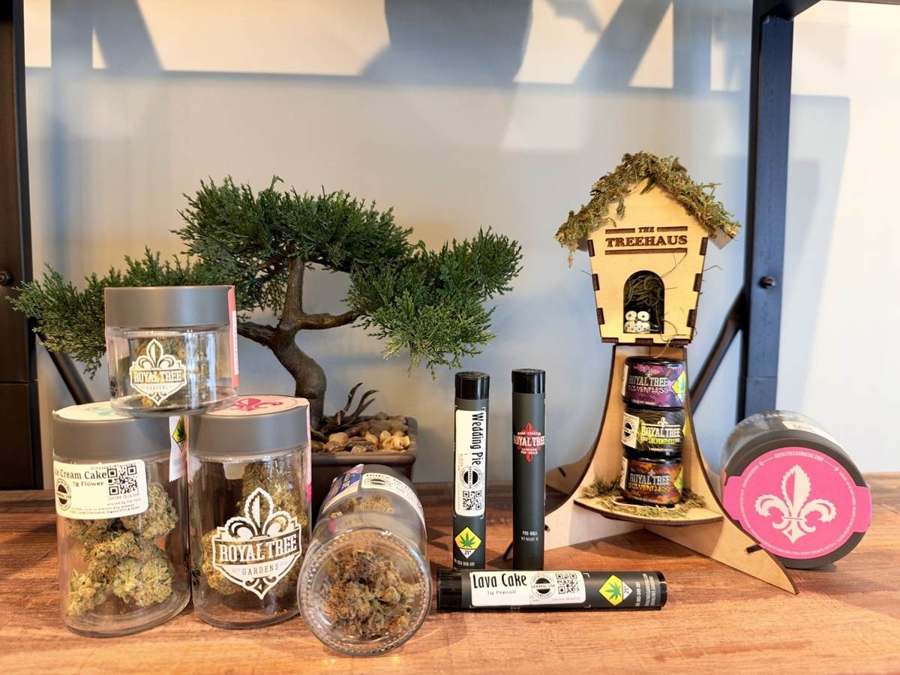 A Washington craft display with bonsai, a birdhouse stand and pre-roll tubes on wooden shelves at Origins